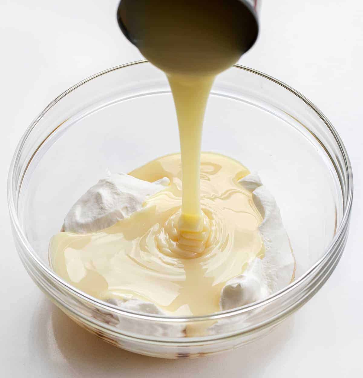 No Churn Vanilla Ice Cream or Four Ingredients Ice Cream. There is no special equipment needed to make this batch of fantastic homemade vanilla ice cream. Ice Cream Recipes, Ice Cream, Vanilla Ice Cream Recipes, How to Make Ice Cream, Food Photography, Ice Cream Food Photography, Homemade Ice Cream with No Machine, dessert, no bake dessert, BBQ Dessert, Cookout Dessert, i am baker, iambaker Pouring Sweetened Condensed Milk into Bowl for No Churn Ice Cream Recipe - 4 Ingredient Ice Cream