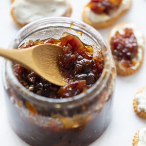 A glass jar of onion bacon jam with a wooden spoon. jam, savory jam, onion jam, bacon jam, onion bacon jam, appetizer jam, savory jam, christmas menu, Christmas hosting, iambaker, i am baker