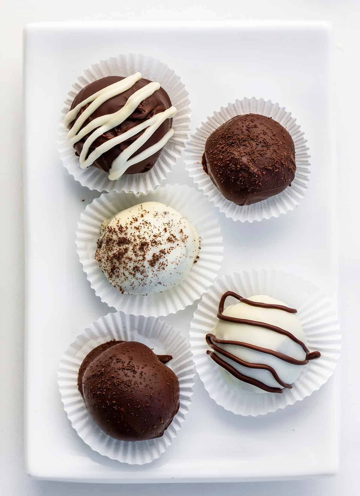 Oreo Truffles are a sweet treat made with crushed Oreo cookies and cream cheese, coated in melted semisweet chocolate. Dessert, Snack, Oreo Balls, Oreo Truffles, Oreo treats, oreo recipes, bbq, superbowl food, finger food, baking, no bake, no bake recipes, i am baker, iambaker Plate of Oreo Truffles on Liners