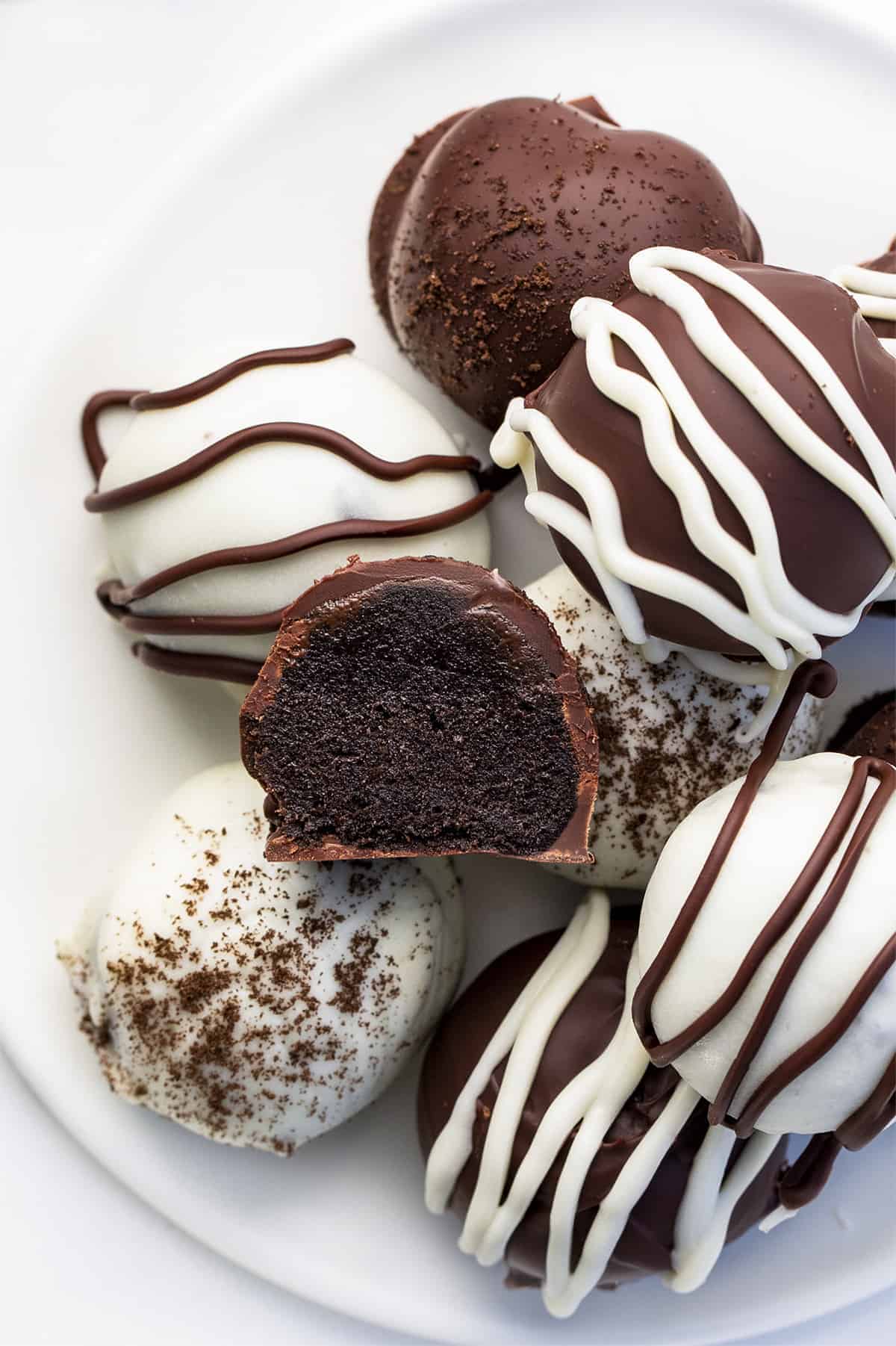 Oreo Truffles are a sweet treat made with crushed Oreo cookies and cream cheese, coated in melted semisweet chocolate. Dessert, Snack, Oreo Balls, Oreo Truffles, Oreo treats, oreo recipes, bbq, superbowl food, finger food, baking, no bake, no bake recipes, i am baker, iambaker Plate of Easy Oreo Truffles with Dark and White Chocolate and One Cut in Half