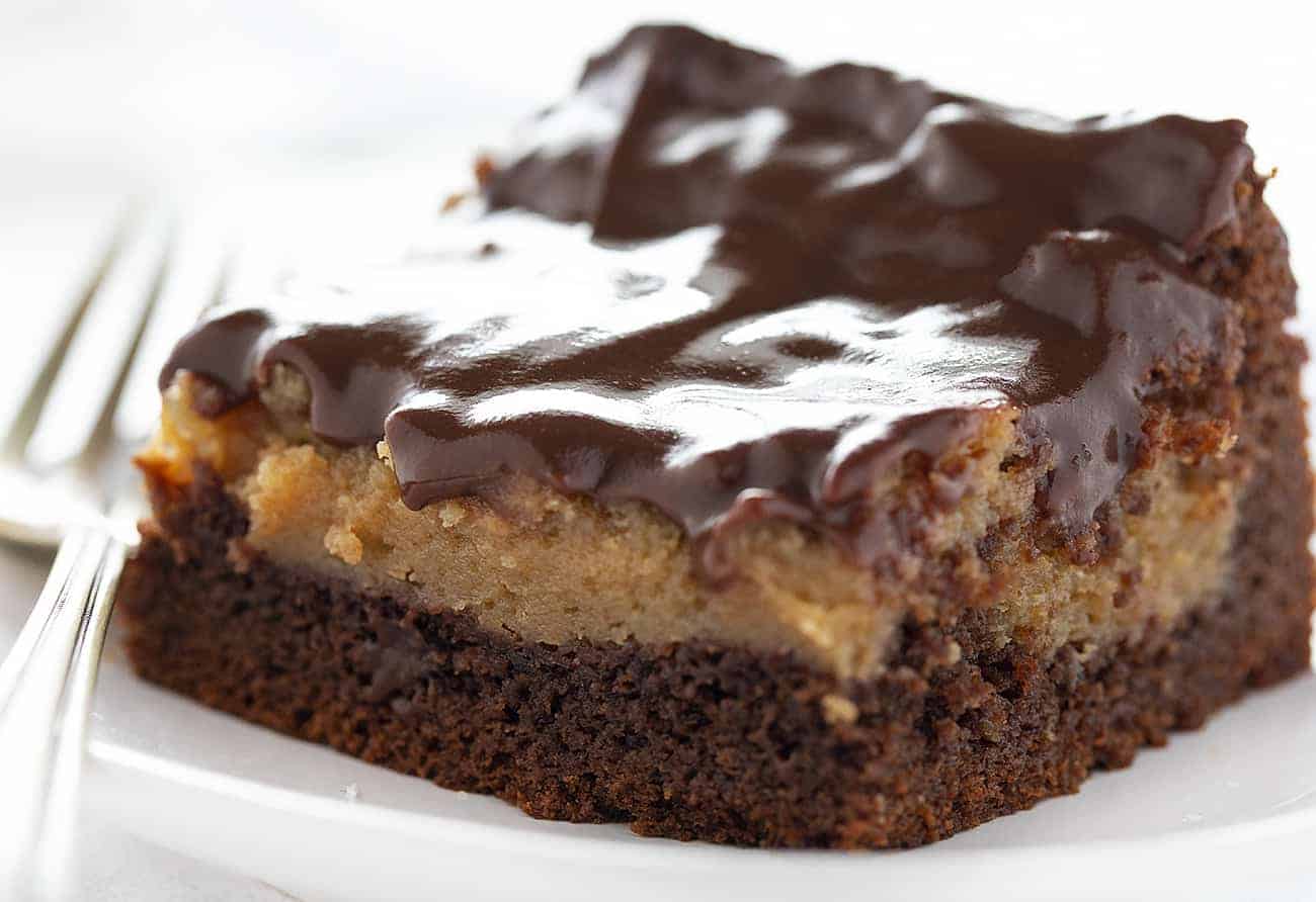 Chocolate Peanut Butter Ooey Gooey Cake takes my Chocolate Ooey Gooey Cake to a new level--a peanut butter level! chocolate peanut butter ooey gooey cake, chocolate ooey gooey cake, ooey gooey butter cake, chocolate peanut butter cake, chocolate cake, how to bake chocolate peanut butter ooey gooey cake, chocolate peanut butter ganache, ganache, dessert recipes, baking, i am baker Piece of Chocolate Peanut Butter Ooey Gooey Cake on a White Plate with Fork