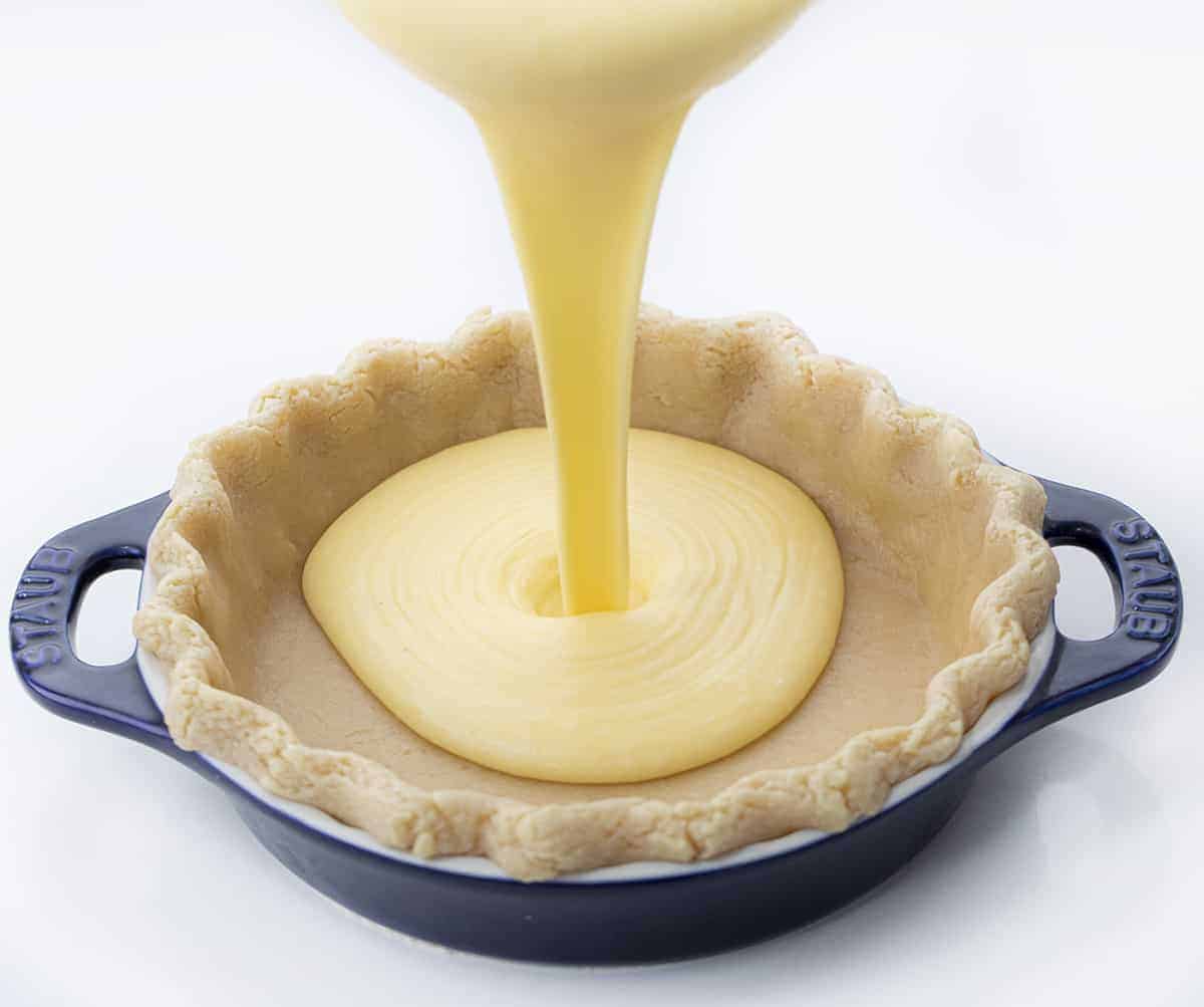 Chess Pie is a rich, sweet, and sugary classic pie that is made with ingredients you probably have on hand and baked in a flaky crust! Pie, Baking, Dessert, Chess Pie, Vintage Dessert, Classic Recipes, Classic Pie Recipes, Homemade Pie Crust, Rustic Pies, i am baker, iambaker Pouring Batter Into Pie Crust for Chess Pie Recipe