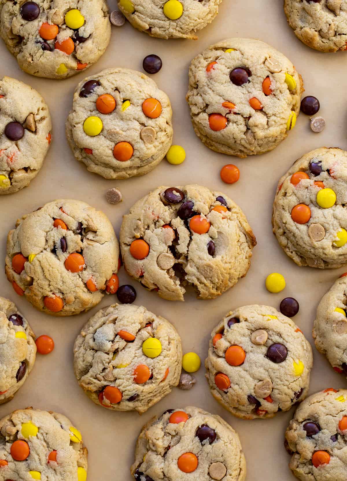 These Reese’s Pieces Peanut Butter Cookies are a cookie lovers dream come true! As you can probably tell, I did not skimp on the peanut butter flavor in these cookies. They are the ultimate peanut butter cookie. There is peanut butter in the dough, as well as peanut butter chips, and two whole cups of Reese’s pieces! These cookies are so gooey in the center and perfectly crisp on the outside! (Perfect for a Christmas charcuterie board or Cookie Exchange!) Reese's Pieces Peanut Butter Cookies on Parchment from Overhead with Middle Cookie Broken in Half.