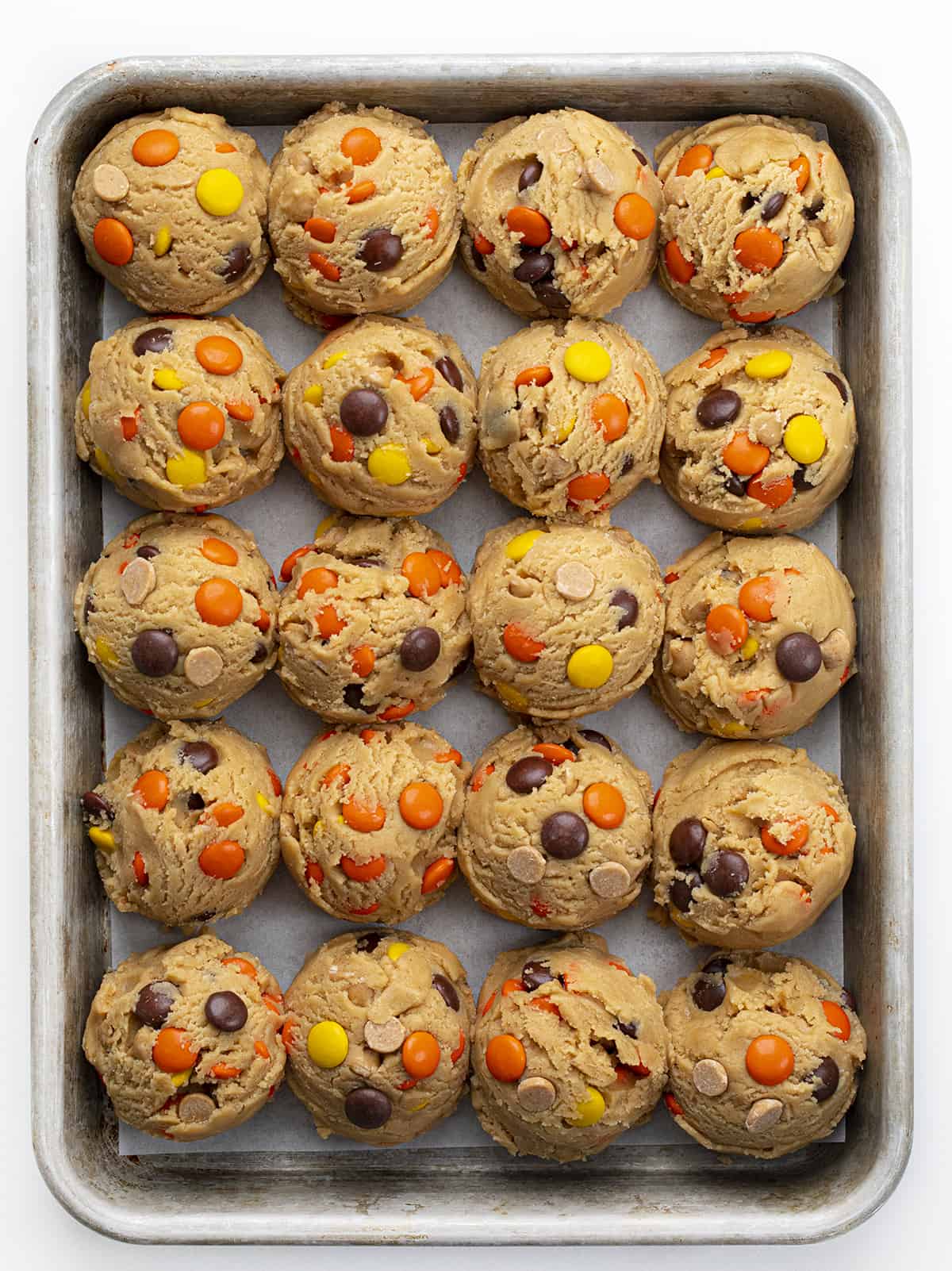 These Reese’s Pieces Peanut Butter Cookies are a cookie lovers dream come true! As you can probably tell, I did not skimp on the peanut butter flavor in these cookies. They are the ultimate peanut butter cookie. There is peanut butter in the dough, as well as peanut butter chips, and two whole cups of Reese’s pieces! These cookies are so gooey in the center and perfectly crisp on the outside! (Perfect for a Christmas charcuterie board or Cookie Exchange!) Reese's Pieces Peanut Butter Cookie Dough in Balls before Baking.