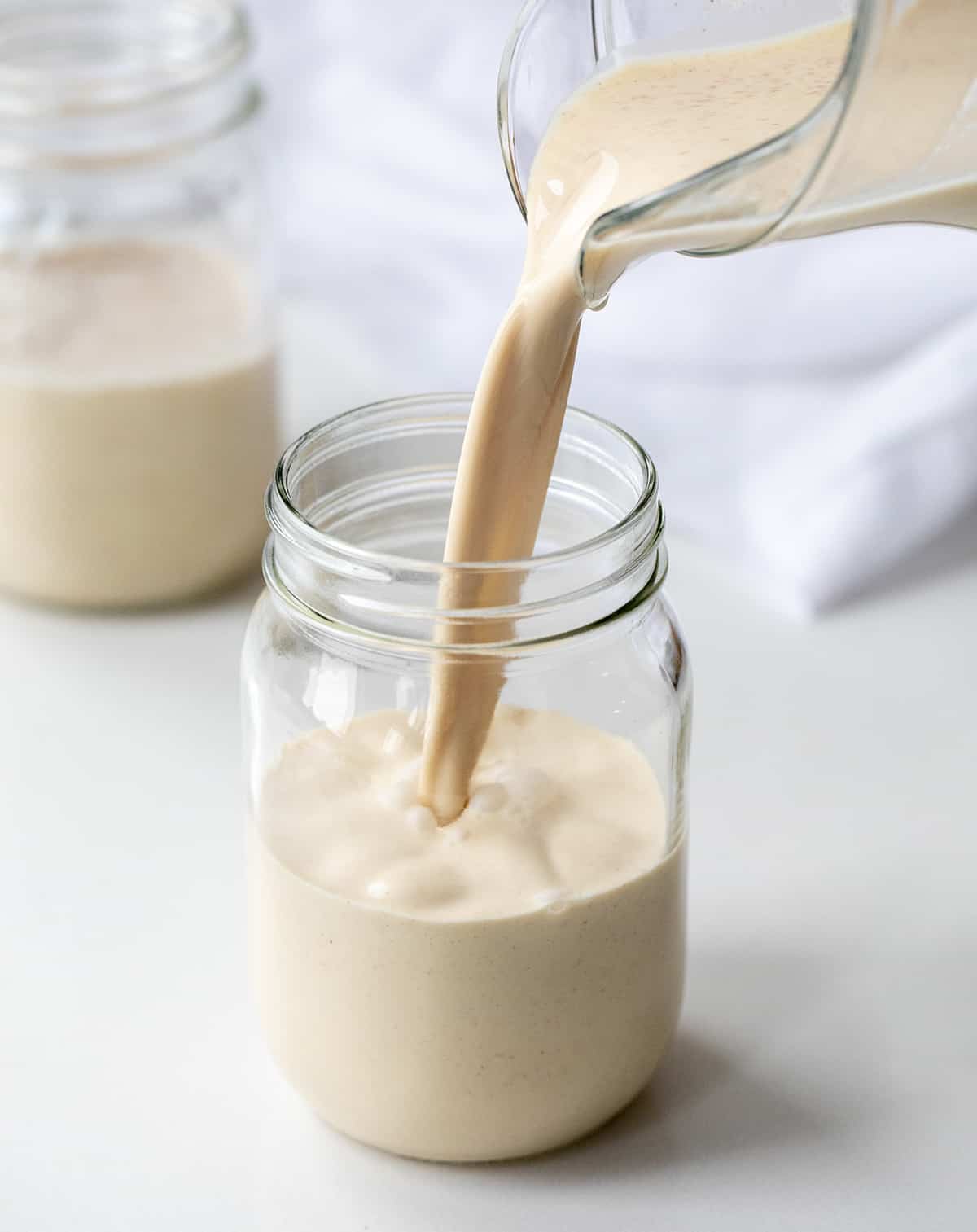 If you love a smooth, creamy cocktail... this is the recipe for you! RumChata is described as a Caribbean rum that blends with Mexican spices and cream. It is the perfect addition to many cocktails and smart to have on hand during the holidays! Perfect for Christmas Cocktails, New Years Eve Cocktails, or even your company Christmas Party! Pouring prepared homemade rumchata to a mug.
