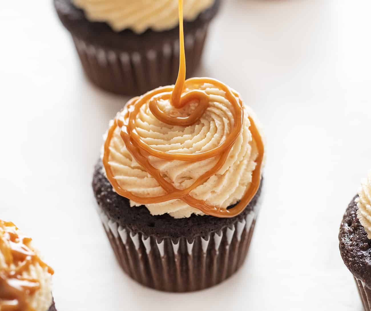 Chocolate Cupcakes with Salted Caramel Buttercream take my Ultimate Chocolate Cupcakes to a whole new salted caramel level! Chocolate Cupcakes, Salted Caramel Buttercream, caramel buttercream, how to make caramel buttercream, chocolate cupcakes, easy chocolate cupcakes, new years eve cupcakes, elegant cupcakes, salted caramel, i am baker Chocolate Cupcakes with Salted Caramel Buttercream Being Piped On