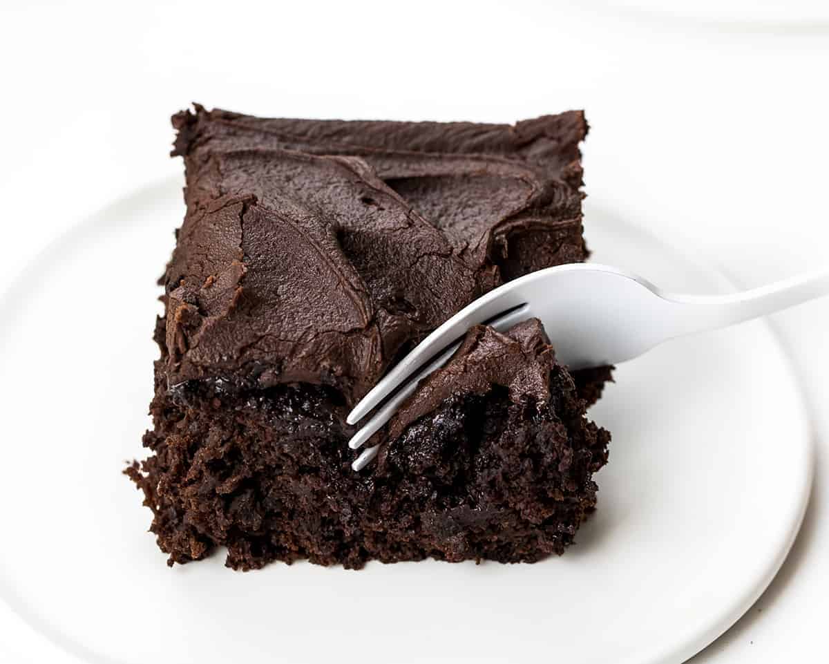 Chocolate Sauerkraut Cake is a soft and moist chocolate cake topped with a thick and creamy chocolate frosting. Chocolate Cake, Sauerkraut Cake, Chocolate Sauerkraut Cake, Vintage Cake, Old Fashioned Cake, Grandma's Chocolate Cake, Baking, Dessert, Chocolate Frosting, recipes, i am baker, iambaker Fork Taking a Bite Out of One Piece of Chocolate Sauerkraut Cake on a White plate.