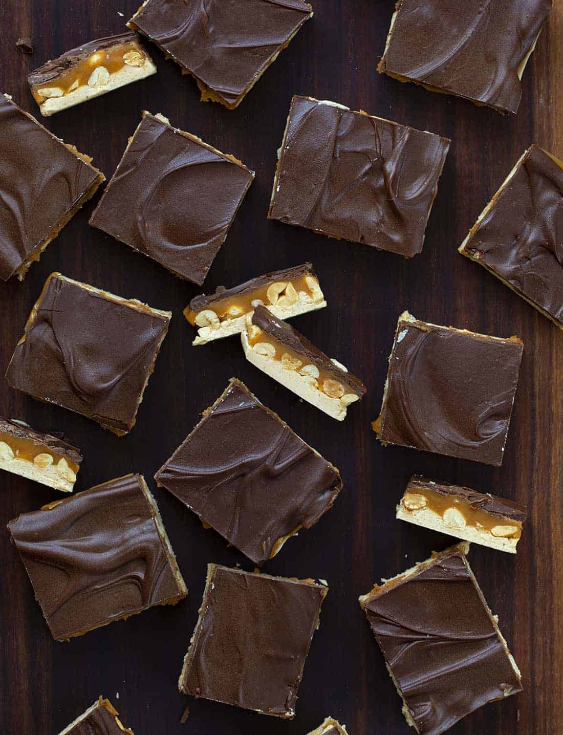 Homemade Snickers is one supersized Snickers bar made with a creamy nougat layer, nutty caramel layer, and a top layer of chocolate. Snickers, Homemade Candy Bars, Candy Bars, Chocolate, Nougat, Peanuts, dessert, snacks, recipes, no bake dessert, i am baker, iambaker Overhead of Homemade Snickers Bars