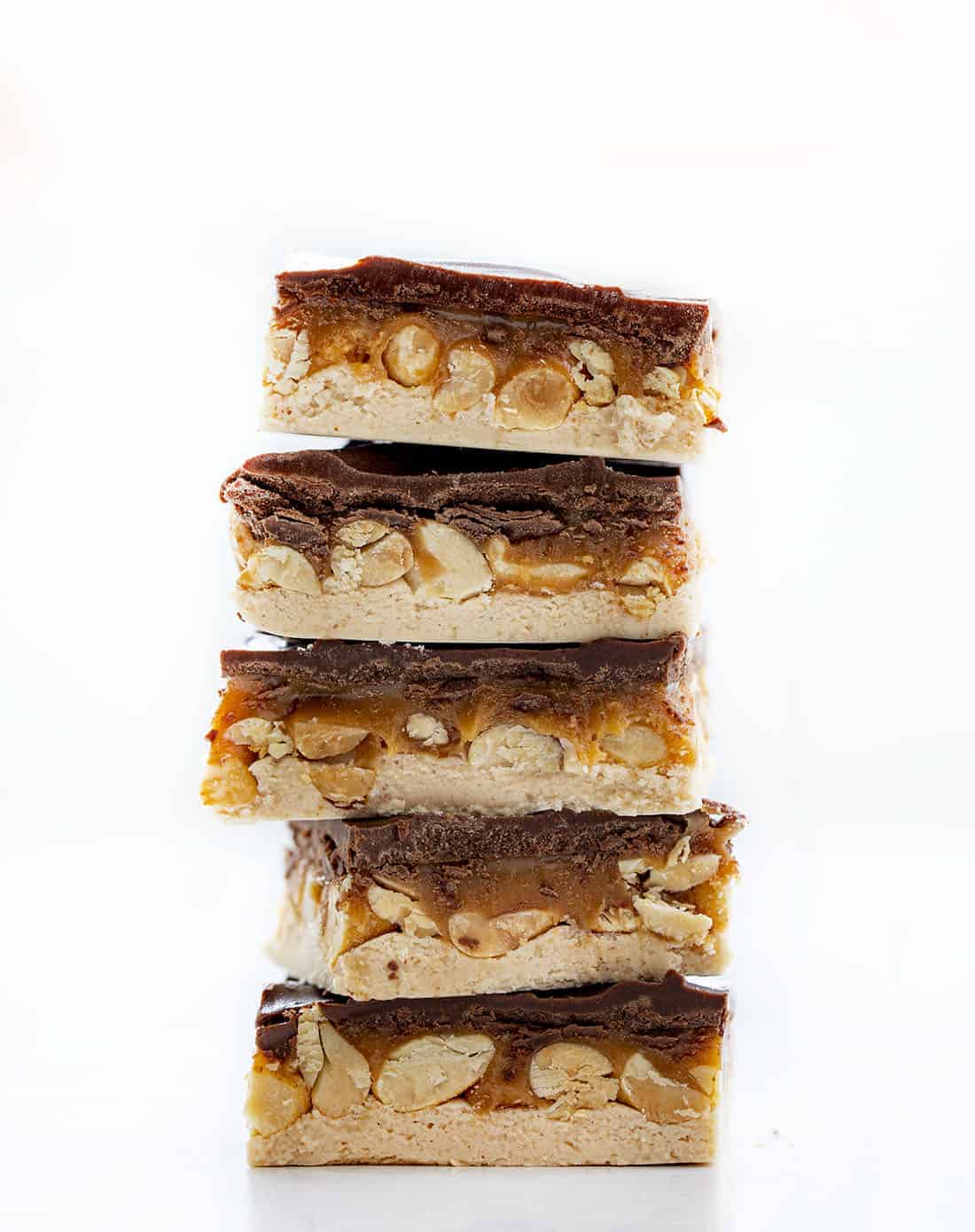 Homemade Snickers is one supersized Snickers bar made with a creamy nougat layer, nutty caramel layer, and a top layer of chocolate. Snickers, Homemade Candy Bars, Candy Bars, Chocolate, Nougat, Peanuts, dessert, snacks, recipes, no bake dessert, i am baker, iambaker Stack of Homemade Snickers Bars