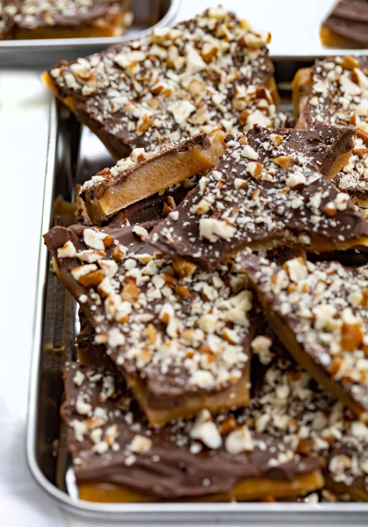 Learn how to make the BEST English Toffee that looks and tastes amazing! Rich buttery toffee covered with milk chocolate and chopped pecans. Just 4 ingredients! English toffee is the perfect holiday candy treat for parties and Christmas gifts. Close up of Chocolate and Nut Covered English Toffee.