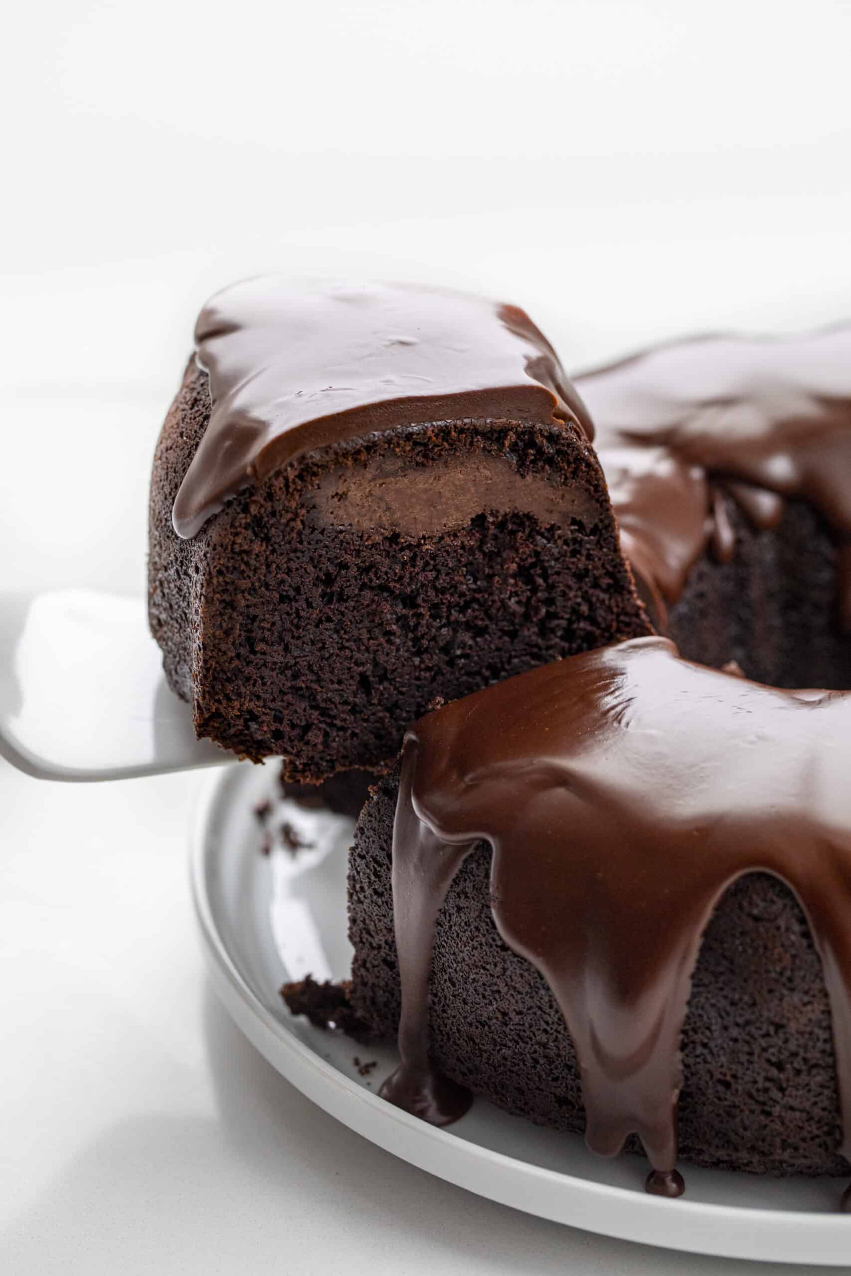 Death By Chocolate Bundt Cake is a chocolate cake with a chocolate cream cheese filling baked in a bundt pan and then topped with chocolate butter ganache. Chocolate Bundt, Triple Chocolate Bundt, Chocolate Cheesecake Chocolate Bundt, Death by Chocolate Bundt Cake, Butter Chocolate Ganache, How to Make Ganache with Just Butter, Chocolate Cream Cheese, Dessert, Baking, Decadent Dessert, Holiday Dessert, Christmas Dessert, New Years Dessert, i am baker, iambaker Picking up a Piece of Chocolate Bundt Cake