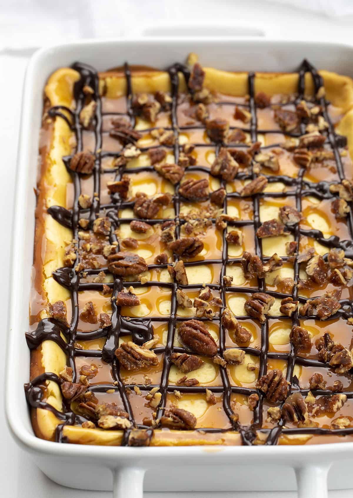 Turtle Cheesecake Bars are creamy dessert bars with a graham cracker crust and cheesecake filling, topped with caramel, candied pecans, and hot fudge. Turtle Cheesecake, Cheesecake Bars, Turtle Cheesecake Bars, Dessert, Cheesecake, Best Cheesecake Recipe, i am baker, iambaker, recipes, baking Turtle Cheesecake Bars in Pan