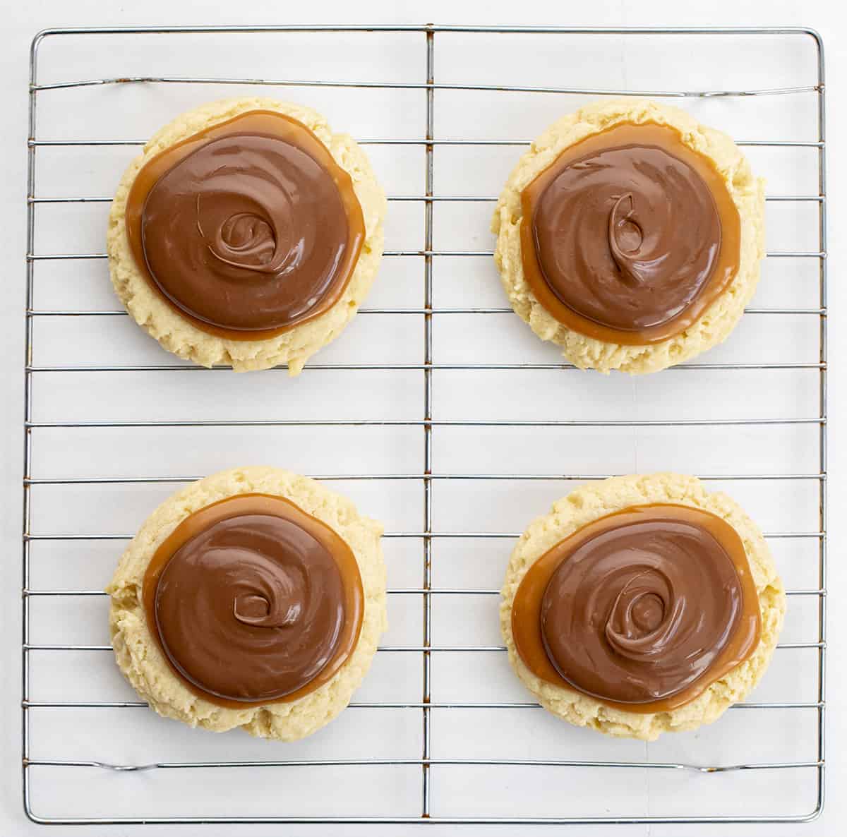 Twix Cookies are large, soft butter cookies topped with caramel sauce and melted milk chocolate. These cookies are like eating a Twix candy bar... but in cookie form! The super-soft cookies are topped with "homemade" caramel and milk chocolate, just like the famous candy bar. Baking, Cookies, Cookie Recipes, Dessert, Caramel Cookies, Caramel Recipe, Milk Chocolate, Kid Approved Snacks, i am baker, iambaker Twix Cookies on a Wire Rack