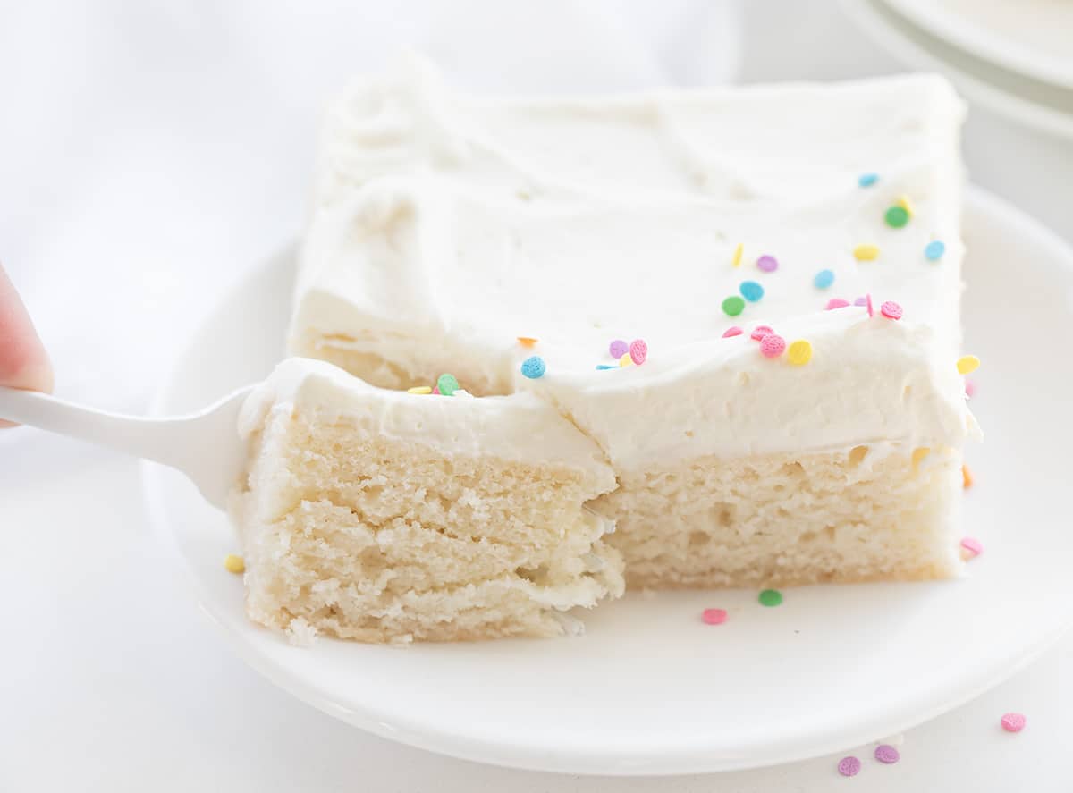 Vanilla Delight Cake (or white cake) is a moist, delicate, and flavorful white sheet cake that is delicious on its own or perfect for your favorite frostings and toppings. It is definitely delightful to snack on, enjoy as a dessert, or share at your next celebration or party! Fork Taking a Bite Out of Vanilla-Delight Cake - White Cake.