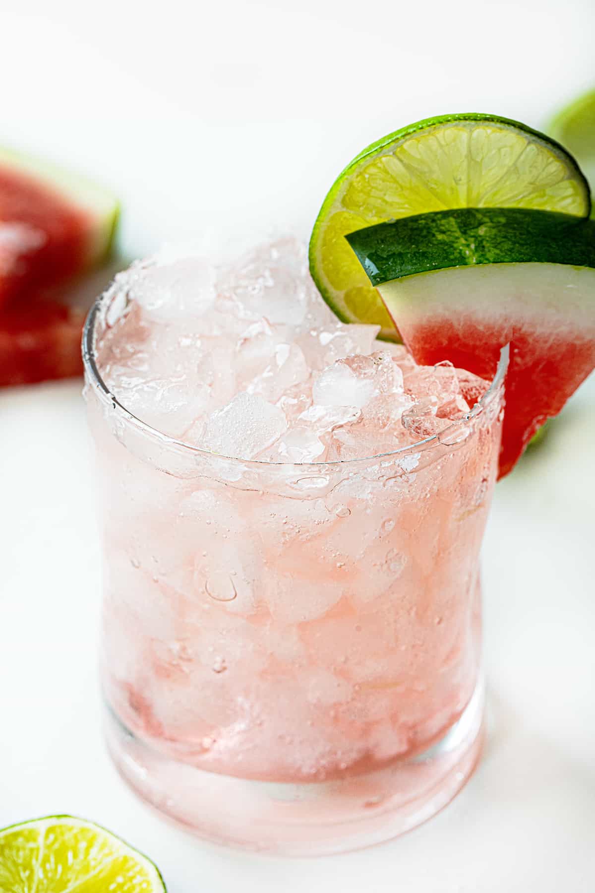 Watermelon Refresher is a delightful fizzy cocktail that combines the flavors of watermelon, lime, and a hint of tequila with a splash of Sprite. It's a perfect drink for a hot summer day, an outdoor gathering, or anytime you are craving a refreshing adult beverage! Glass Filled with a Watermelon Refresher Cocktail with a Watermelon Wedge and Lime.