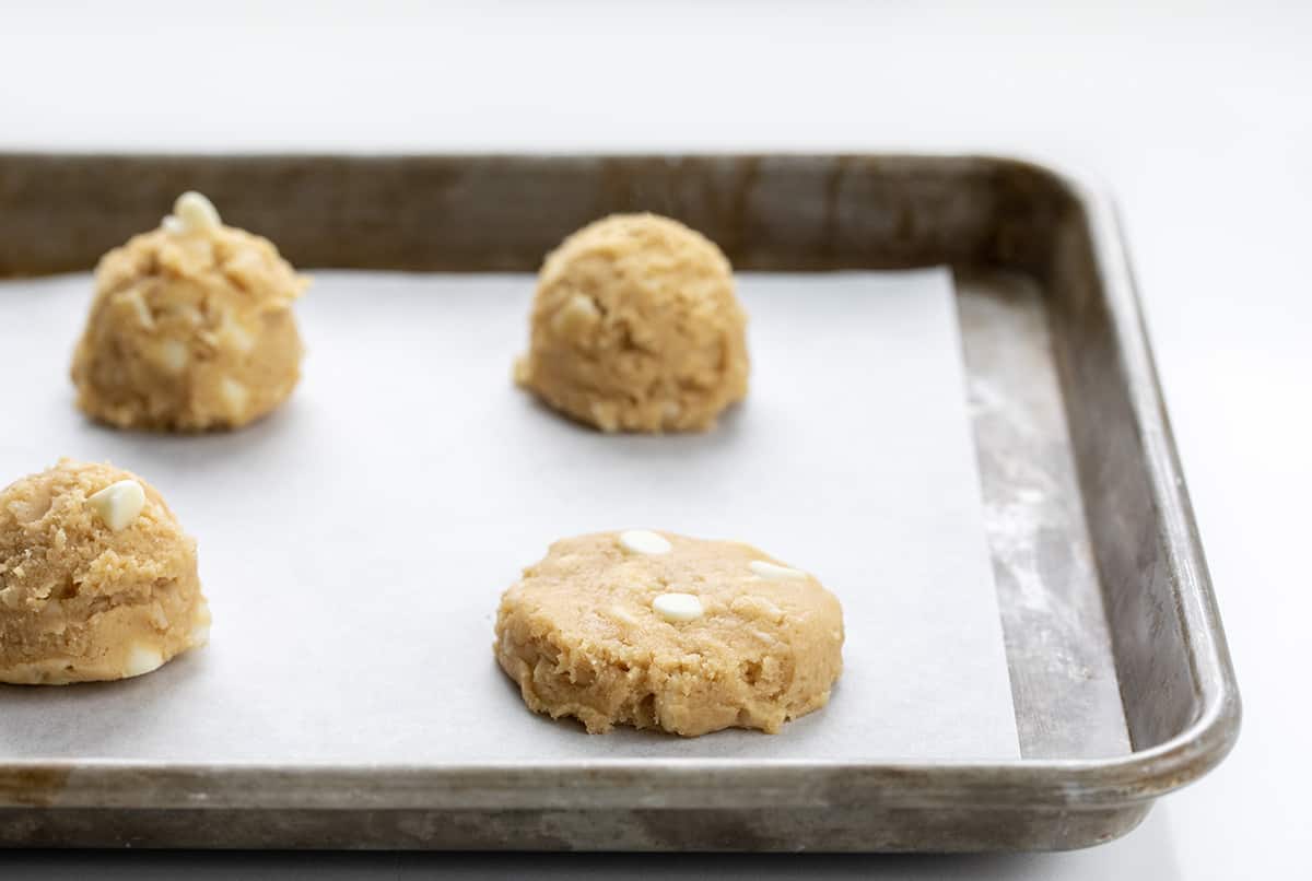 White Chocolate Macadamia Nut Cookies have the rich, buttery flavor of macadamia nuts and the sweet creaminess of white chocolate. These soft, chewy cookies are loaded with white chocolate chips and chopped macadamia nuts for the perfect balance of flavors, great for any occasion! One White Chocolate Macadamia Nut Cookie Pressed Down Before Baking.